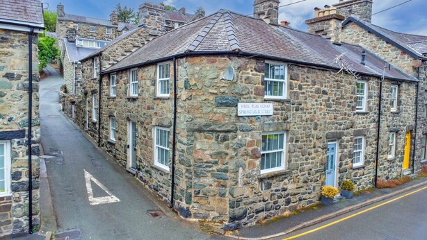 Un edificio de piedra con un cartel que dice 'HEOL PLAS UCHAF SPRINGFIELD STREET'.