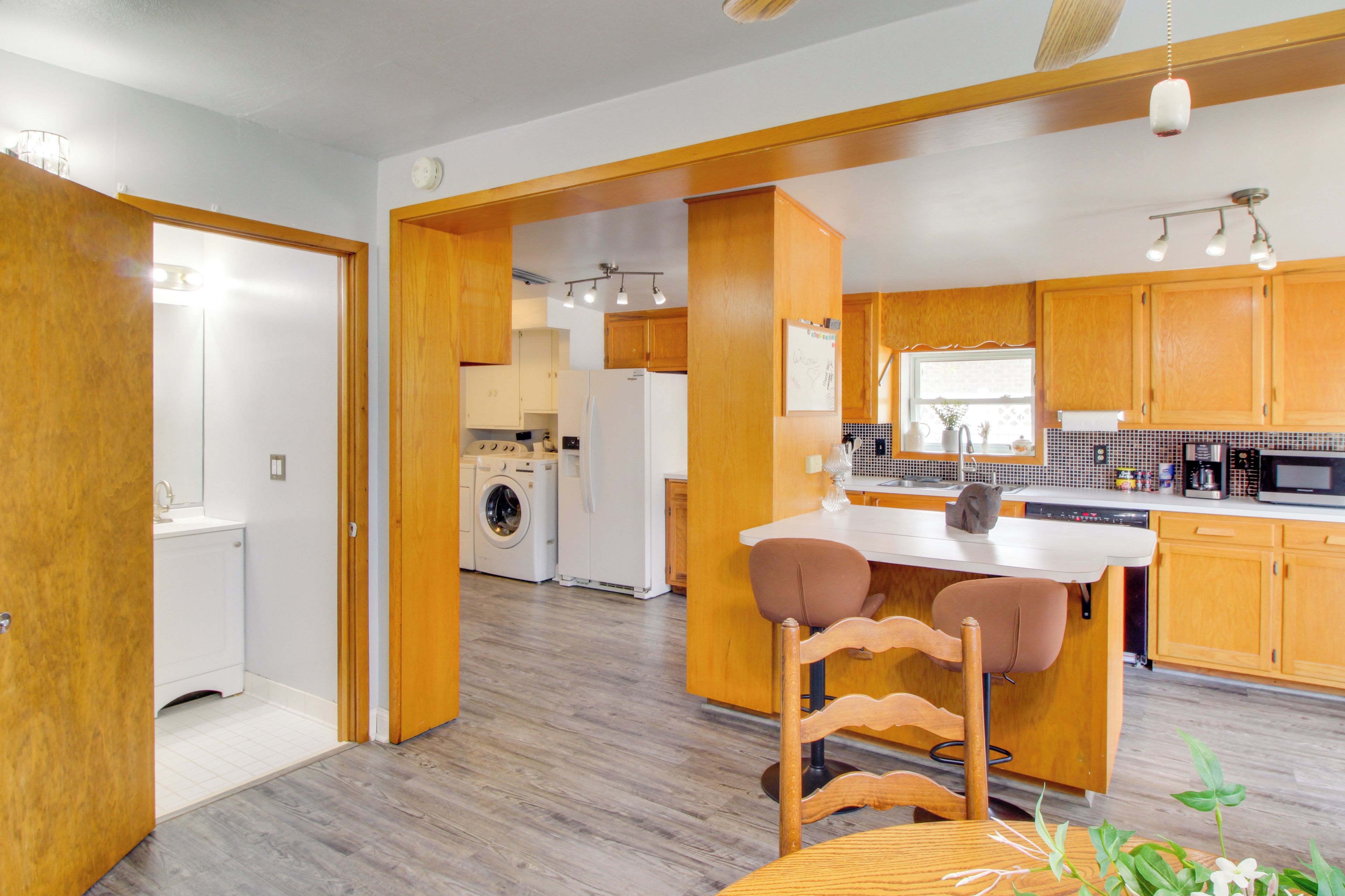 A modern kitchen with wooden cabinets, a central island, and a built-in washing machine.