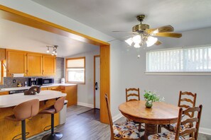 Una cocina moderna con armarios de madera, microondas y comedor con mesa y sillas de madera.