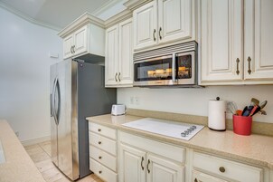 Una cocina con armarios blancos, un refrigerador de acero inoxidable, un microondas y un tostador.