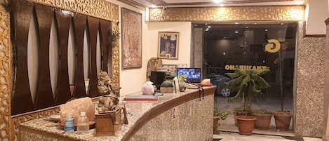 Uma área de recepção de hotel com balcão curvo, painéis decorativos na parede e um balcão de atendimento.