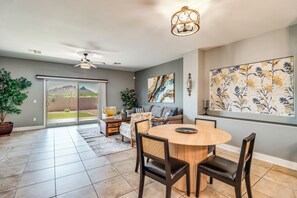 A spacious living area with a dining table, chairs, a ceiling fan, and a large window with a view of a mountain. - Walk to Tucson Trails! Private Yard w/ Views (Tucson)