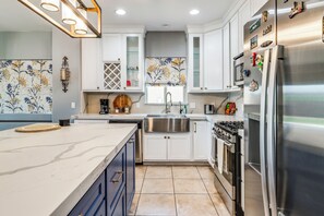 A modern kitchen with a central island, stainless steel appliances, and decorative tiles. - Walk to Tucson Trails! Private Yard w/ Views (Tucson)