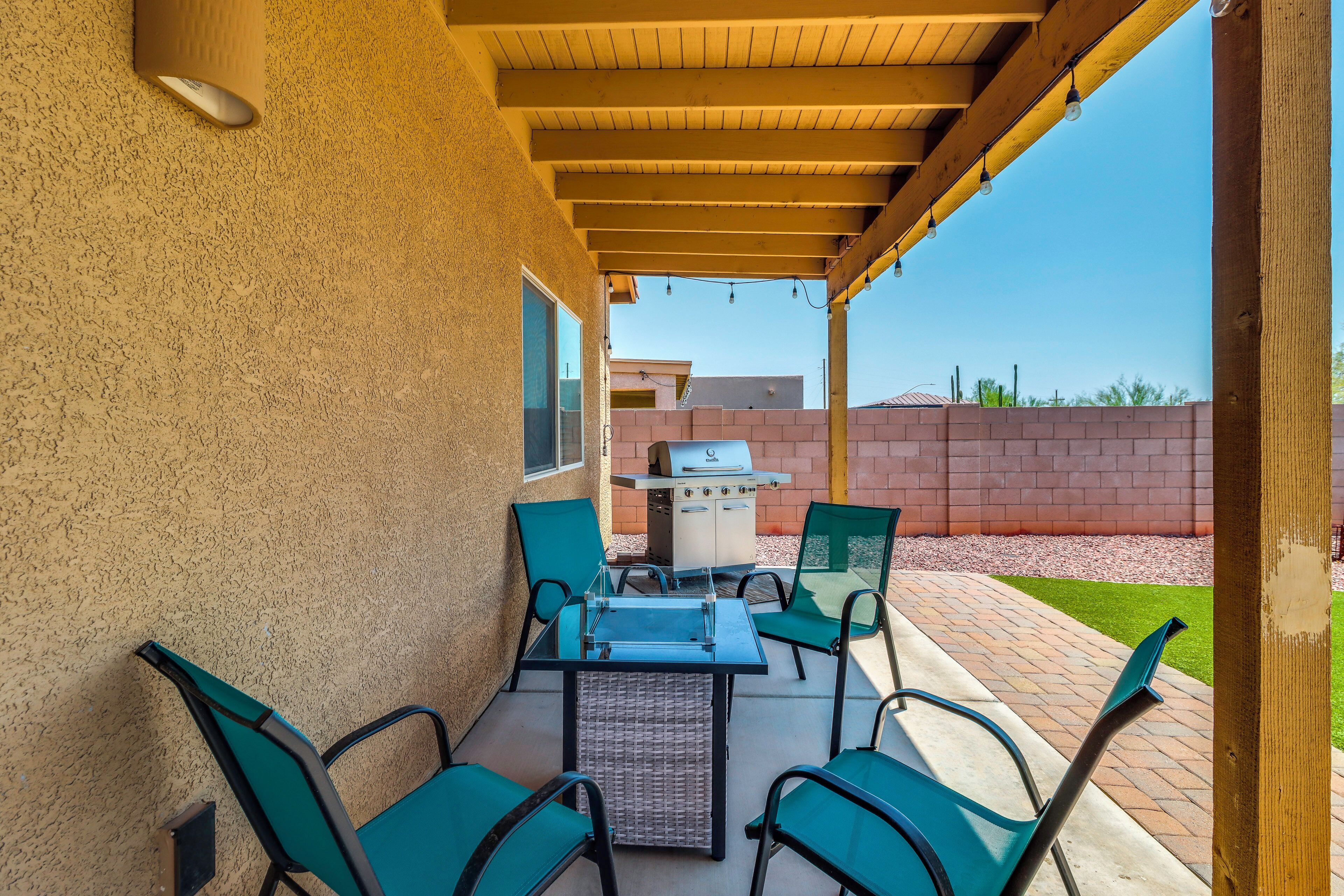 An outdoor patio with a grill, chairs, and a table.