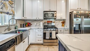 A modern kitchen with white cabinetry, stainless steel appliances, and a marble countertop. - Walk to Tucson Trails! Private Yard w/ Views (Tucson)