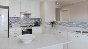 Una cocina moderna con armarios blancos, estufa a gas, horno empotrado y salpicadero de azulejos.