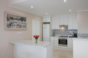 Una cocina moderna con armarios blancos, una isla central y salpicadero de azulejos.