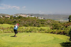 A golf course with a clear view of a residential area in the background. - Afternoon Delight NT3 (Knysna)