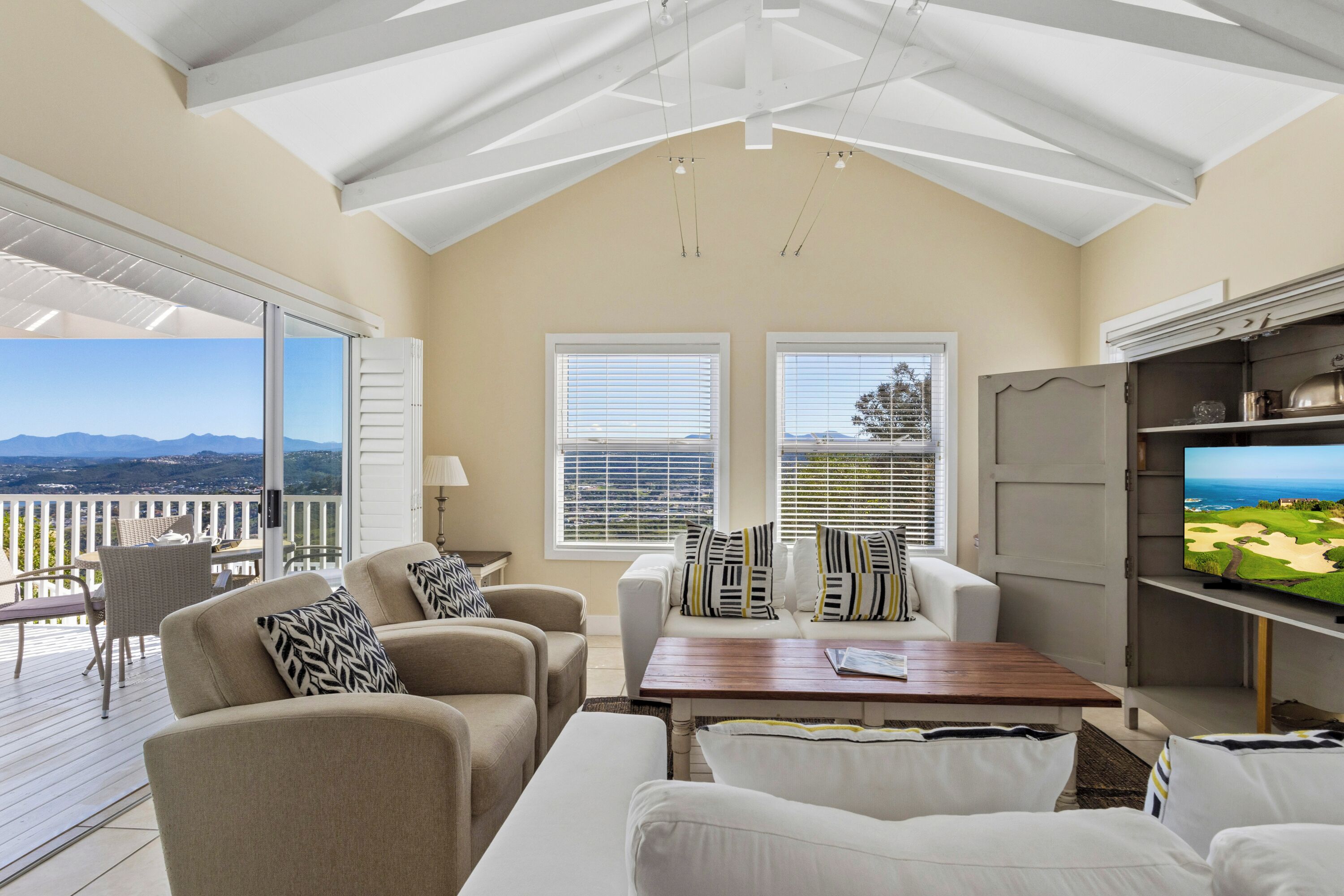A spacious living area with a high ceiling, large windows, and a view of the outdoors.