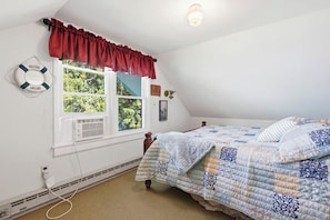 A bedroom with a bed, a window with a red valance, a life preserver decoration, and a ceiling light. - Lakefront Paradise on Lake Wallenpaupack w/ Dock (Hawley)