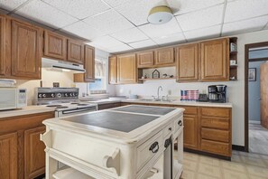 A kitchen with wooden cabinets, a stove, a microwave, and a coffee maker. - Lakefront Paradise on Lake Wallenpaupack w/ Dock (Hawley)