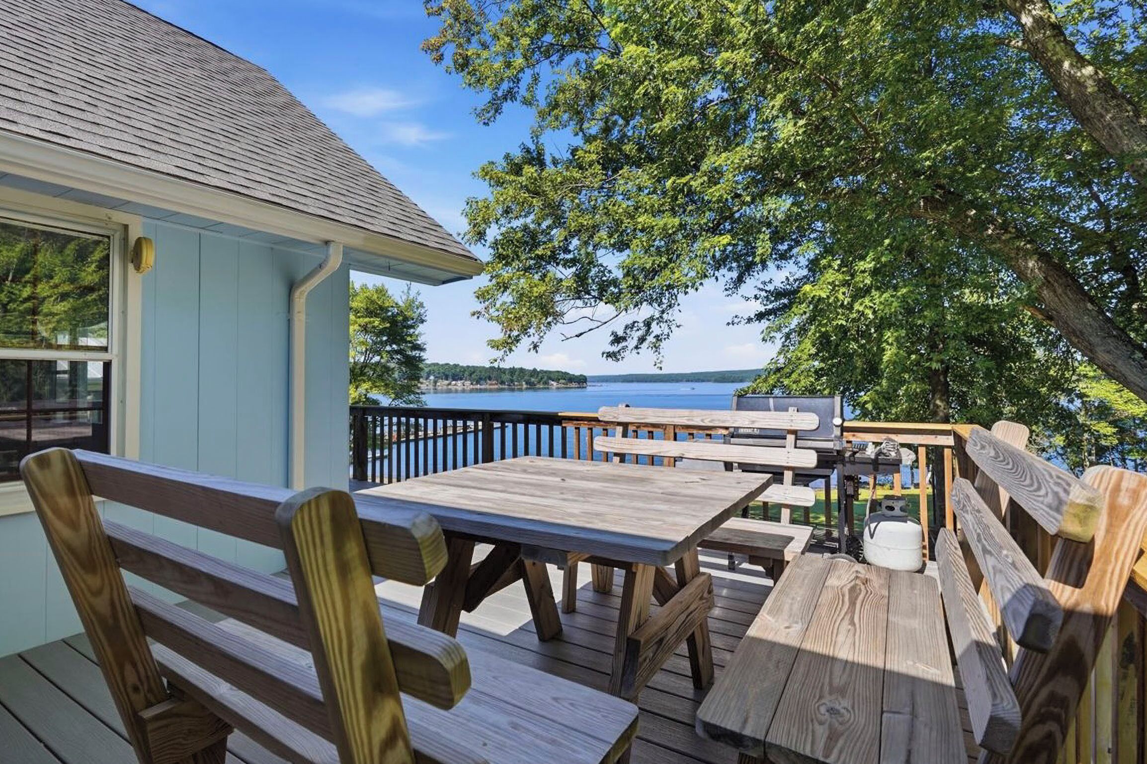 An outdoor deck with wooden benches and tables, overlooking a body of water.