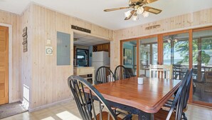 A dining area with a wooden table and chairs, a ceiling fan, and a view through glass doors. - Lakefront Paradise on Lake Wallenpaupack w/ Dock (Hawley)