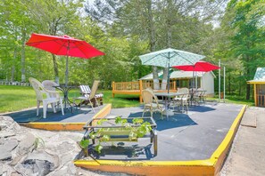Eine Terrasse im Freien mit Tischen und Stühlen, umgeben von einem Holzdeck und einem kleinen Gebäude.