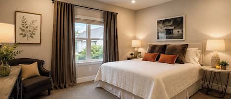 A bedroom with a bed, a ceiling fan, a window with curtains, a desk with a lamp, and a framed picture on the wall.