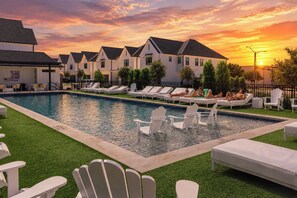 A swimming pool with lounge chairs and a sunset in the background. - Magnolia Manor at College Station & Texas A&M (College Station)