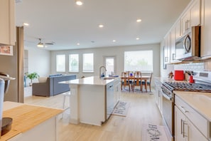 A modern kitchen with a central island, a dining area with a table and chairs, and a living area with a sofa. - Fenced Yard! Family Getaway, Near Texas Ski Ranch (San Marcos)