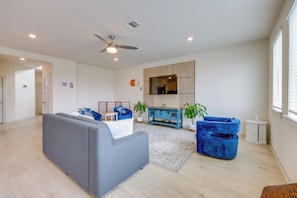 A modern living room with a grey sofa, blue armchairs, a blue cabinet, and a ceiling fan. - Fenced Yard! Family Getaway, Near Texas Ski Ranch (San Marcos)