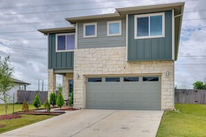 Une maison à deux étages avec une façade en pierre, un garage et une pelouse bien entretenue.