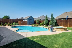A backyard with a swimming pool, a hot tub, and a wooden fence.