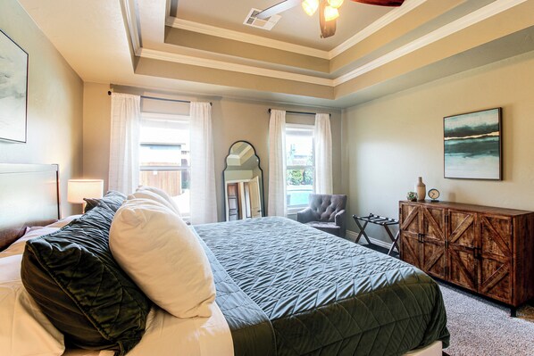 A hotel room with a bed, a chair, a wooden cabinet, and a painting on the wall.