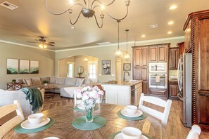 A spacious kitchen with wooden cabinets, a central island, and a dining area with a round table set for four.