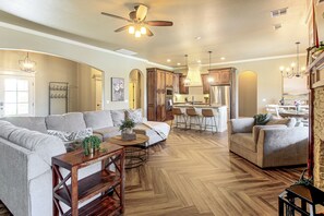 A spacious living room with a large sectional sofa, a wooden coffee table, and a herringbone-patterned hardwood floor. - Gateway to Downtown Okc! Elegant Home (Yukon)