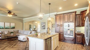 A spacious kitchen with a central island, wooden cabinets, and stainless steel appliances. - Gateway to Downtown Okc! Elegant Home (Yukon)