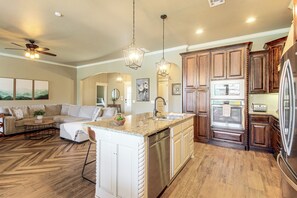 A spacious kitchen with a central island, wooden cabinets, and stainless steel appliances.