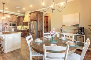 A modern kitchen with a central island, stainless steel appliances, and a dining area with a round table and chairs.