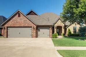 A residential house with a brick facade, two garage doors, and a well-maintained lawn.