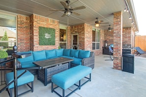 An outdoor patio with a sectional sofa, a table, and a grill area.