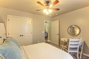 A bedroom with a bed, a chair, a desk, and a ceiling fan.