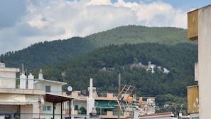 A residential area with buildings, a green hill in the background, and a clear sky.