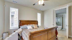 Ein Schlafzimmer mit einem hölzernen Bett, einem Deckenventilator und einem durch eine offene Tür einsehbaren Badezimmer.