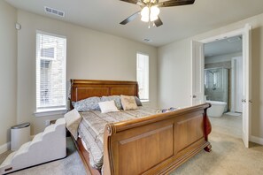 Ein Schlafzimmer mit einem hölzernen Bett, einem Deckenventilator und einem durch eine offene Tür einsehbaren Badezimmer.