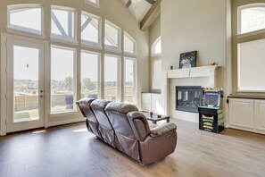 Ein geräumiges Wohnzimmer mit Ledersessel, Kamin und großem Fenster mit Blick auf einen Garten.