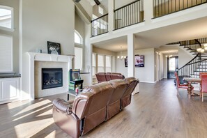A spacious living room with a fireplace, leather recliner, and a staircase leading to an upper level.