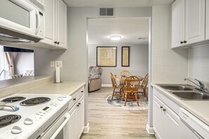 Una cocina moderna con armarios blancos, estufa integrada y un fregadero.