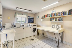 Un cuarto de lavandería con lavadora, secadora y una estantería con libros.
