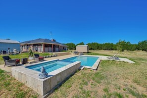 A backyard with a swimming pool, outdoor furniture, and a covered patio area.