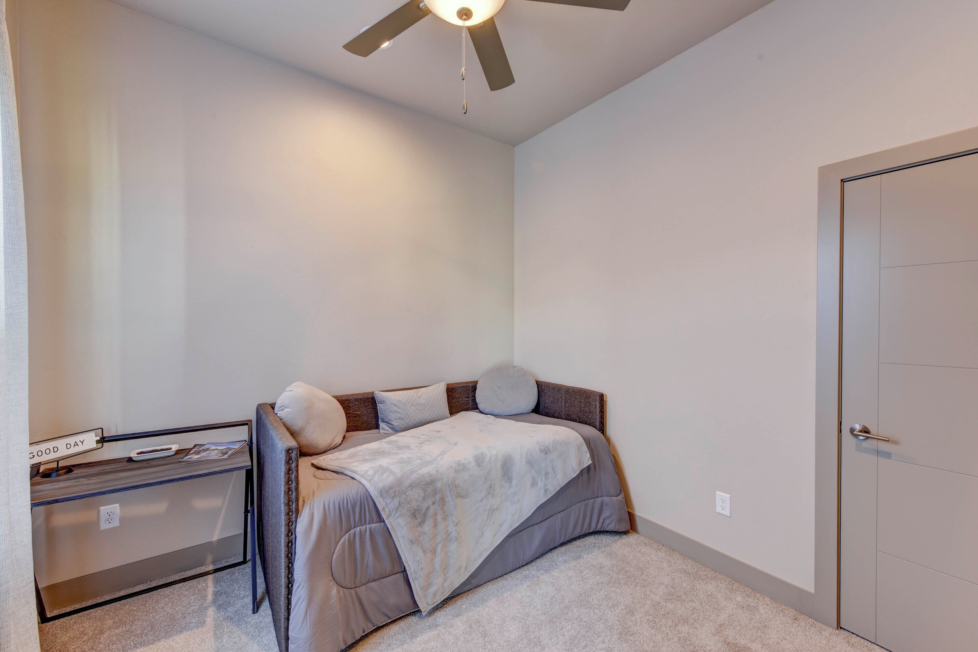 A bedroom with a bed, a desk, a chair, and a door.