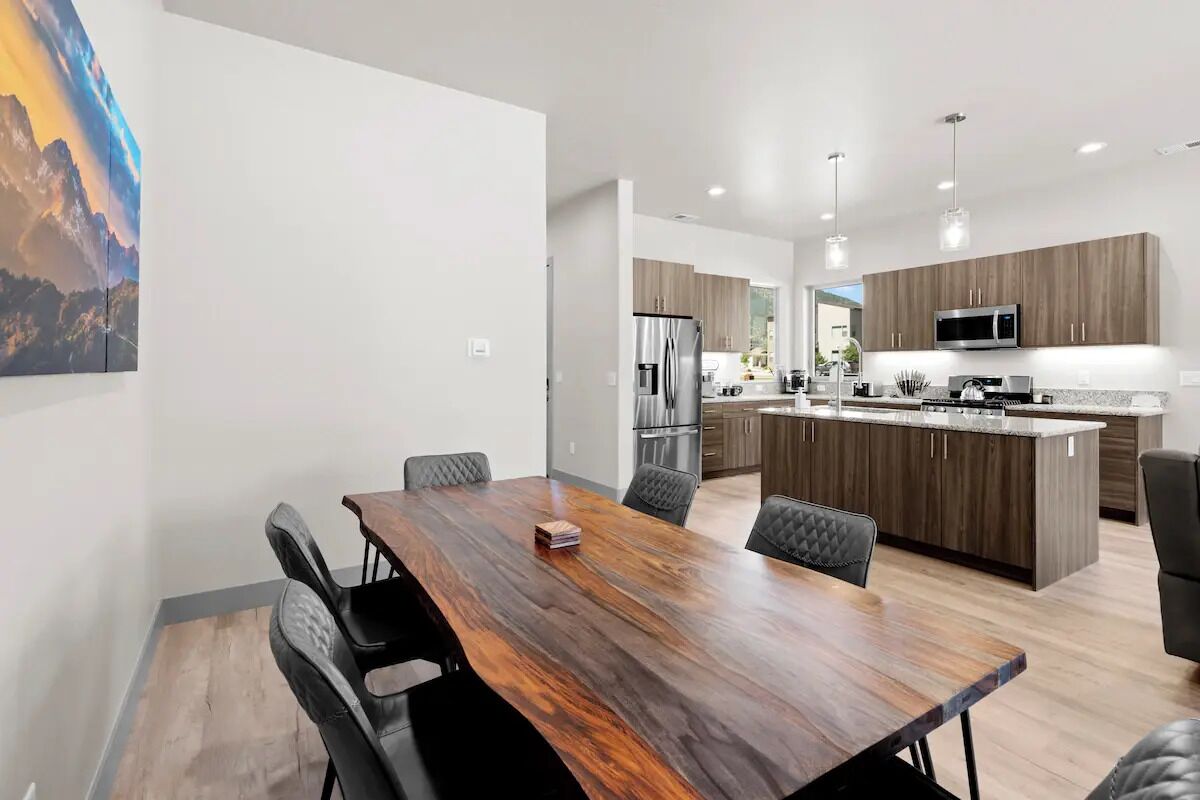 Una cocina moderna con gabinetes de madera, electrodomésticos de acero inoxidable e iluminación colgante.
