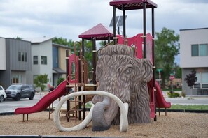 Ein Spielplatz mit einer Löwenskulptur, Rutschen und Klettergerüsten.