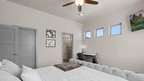 Quarto com cama, escrivaninha e chuveiro.