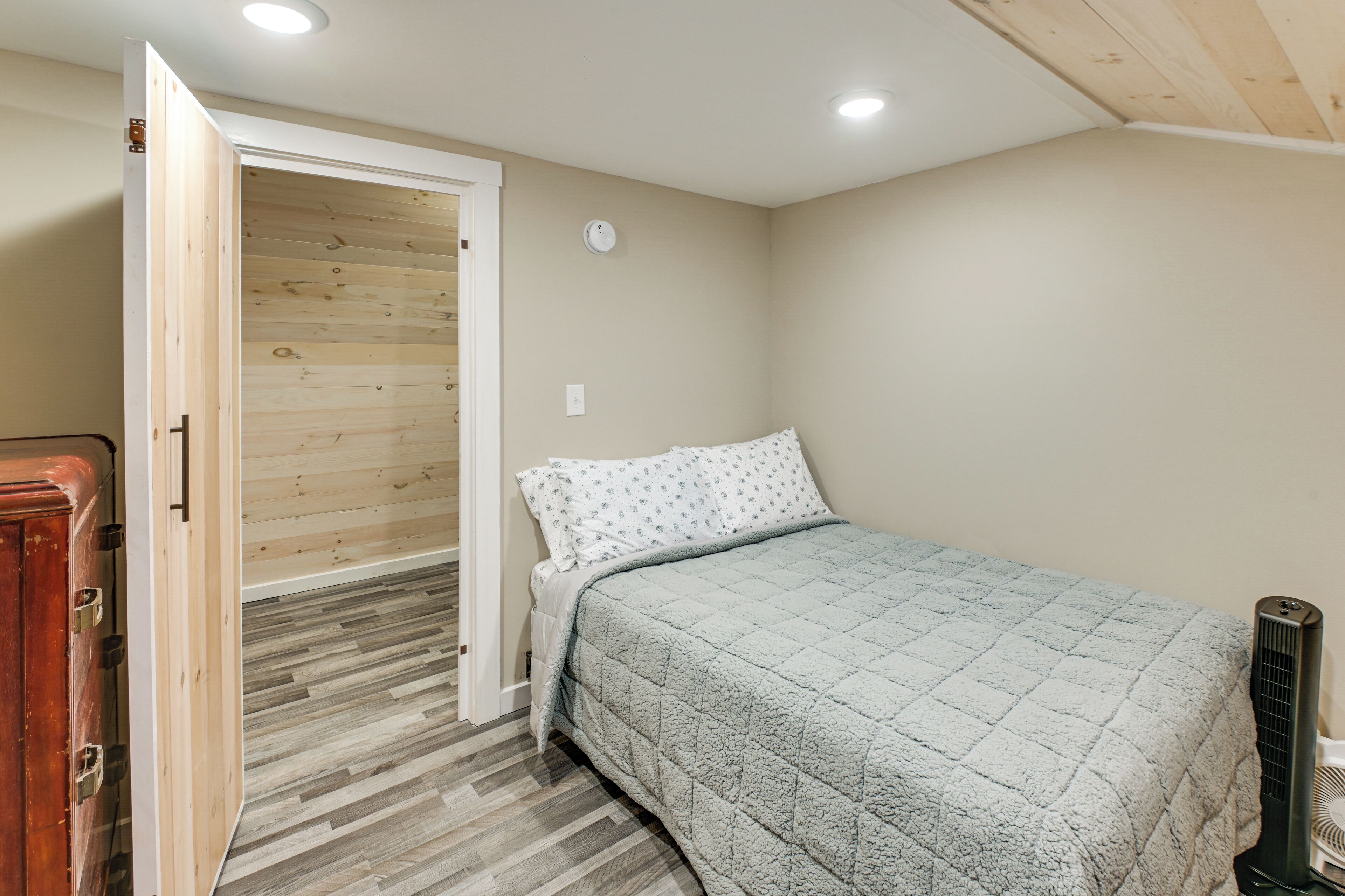 A bedroom with a bed, a door leading to a wooden closet, and a radiator.