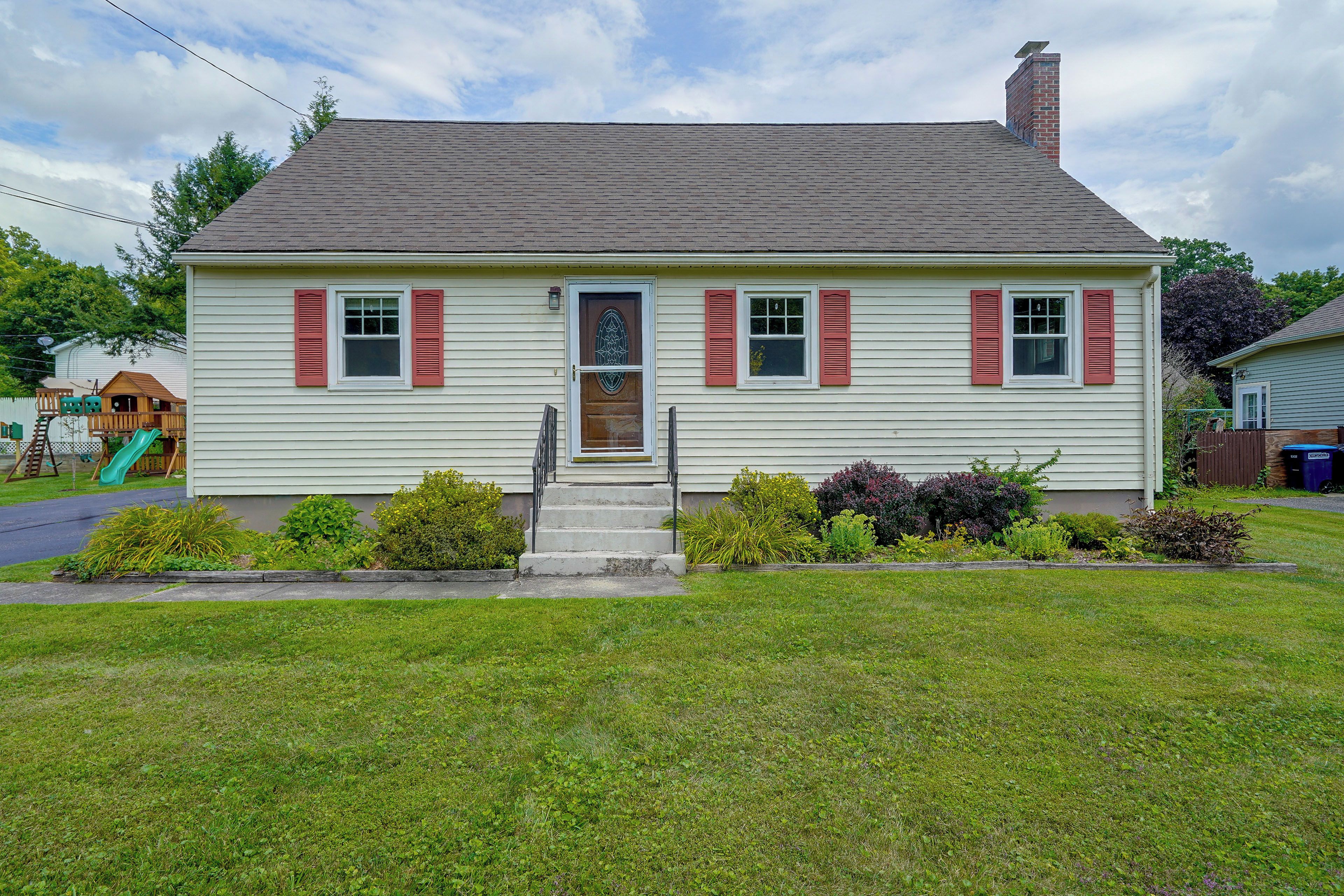 A single-story house with a front porch, a small front yard, and a visible satellite dish.