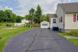 A residential driveway leading to a garage, a small playhouse, and a house with a garage door. - Fall Fun in the Berkshires: Yard, Patio, Playset (Pittsfield)