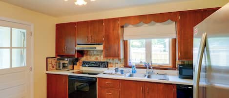 Una cocina con armarios de madera, un refrigerador de acero inoxidable, horno empotrado y lavavajillas.