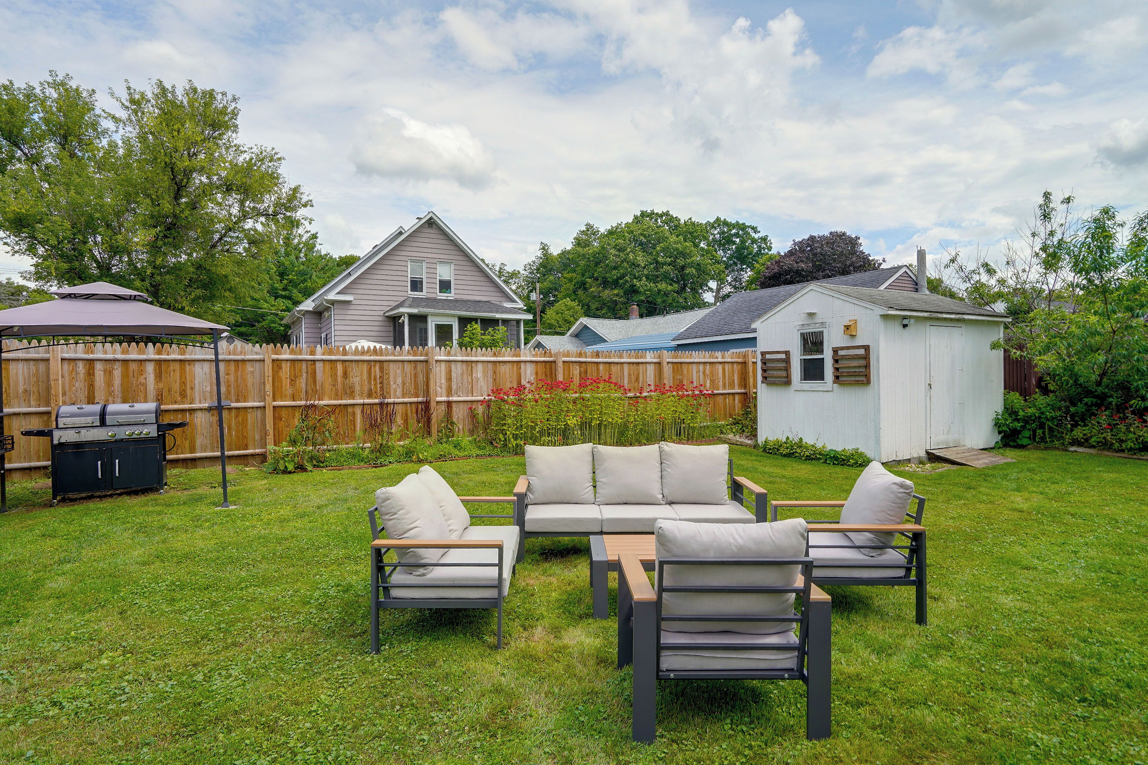 A backyard with a patio set, a barbecue grill, and a wooden fence.
